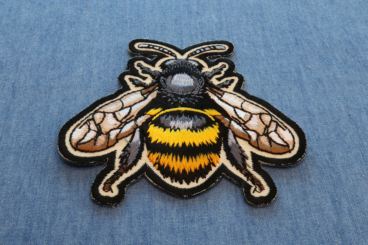 Bee embroidered patch laid flat on denim