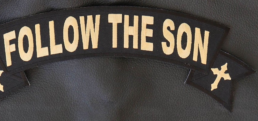 Close-up of Follow the Son rocker lettering, cross and embroidered edge